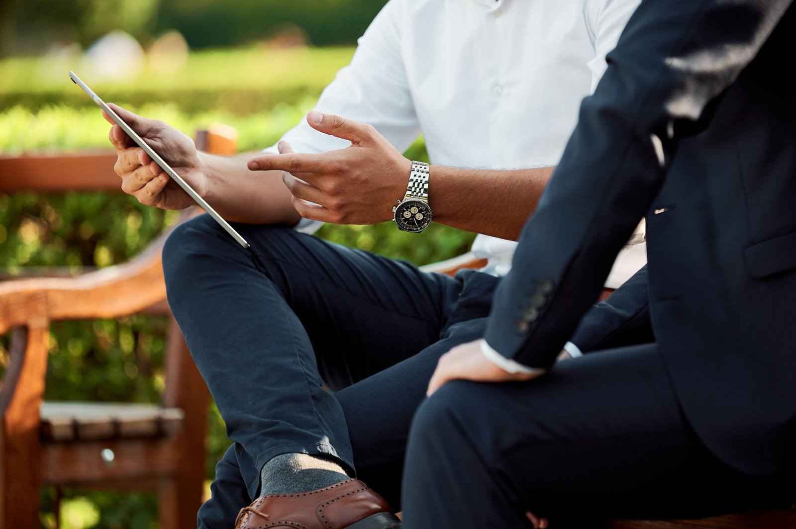 Picture of two men sitting on a bench and examining something on a tablet