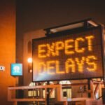 Road block sign in front of a building that says Expect Delays