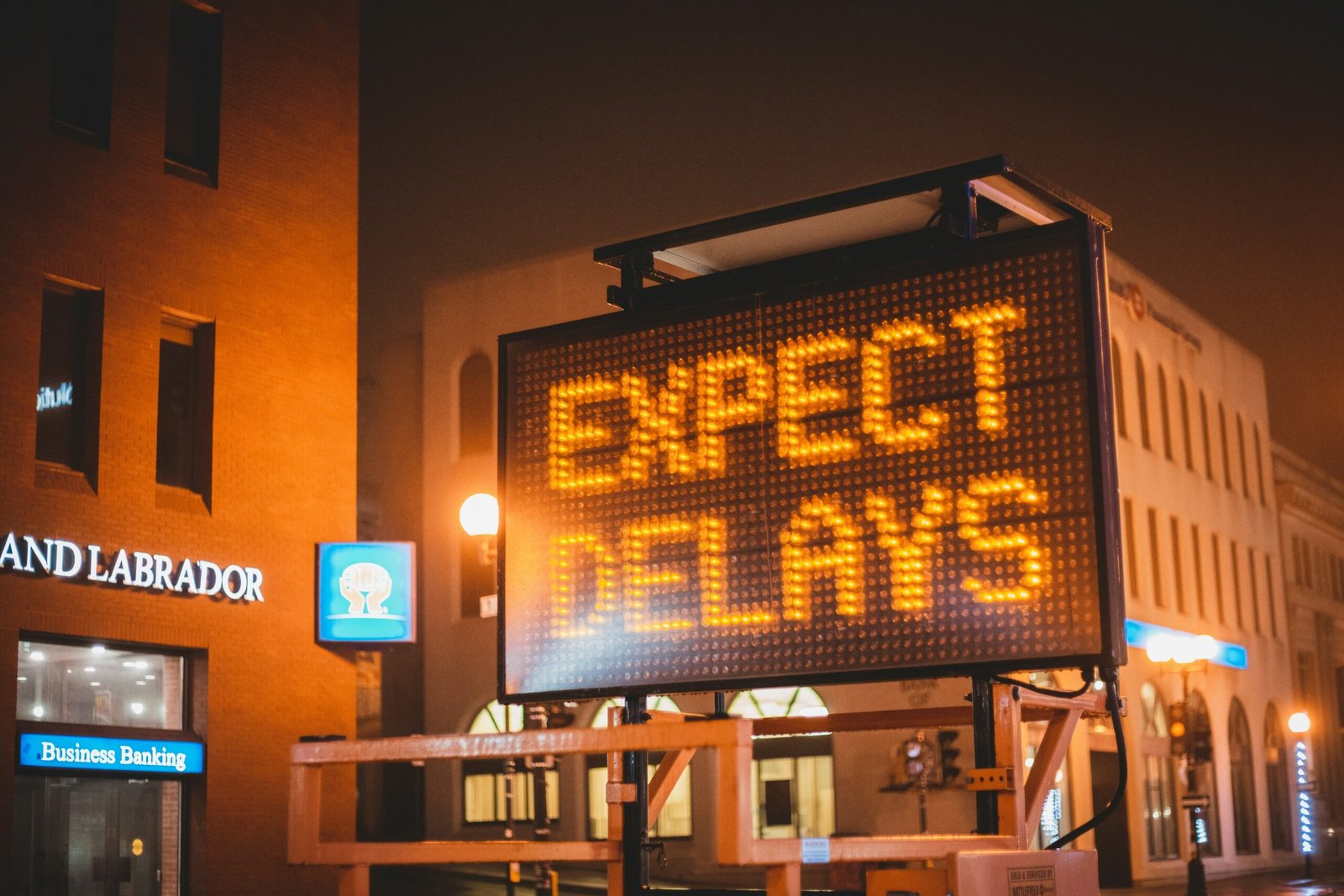Road block sign in front of a building that says Expect Delays