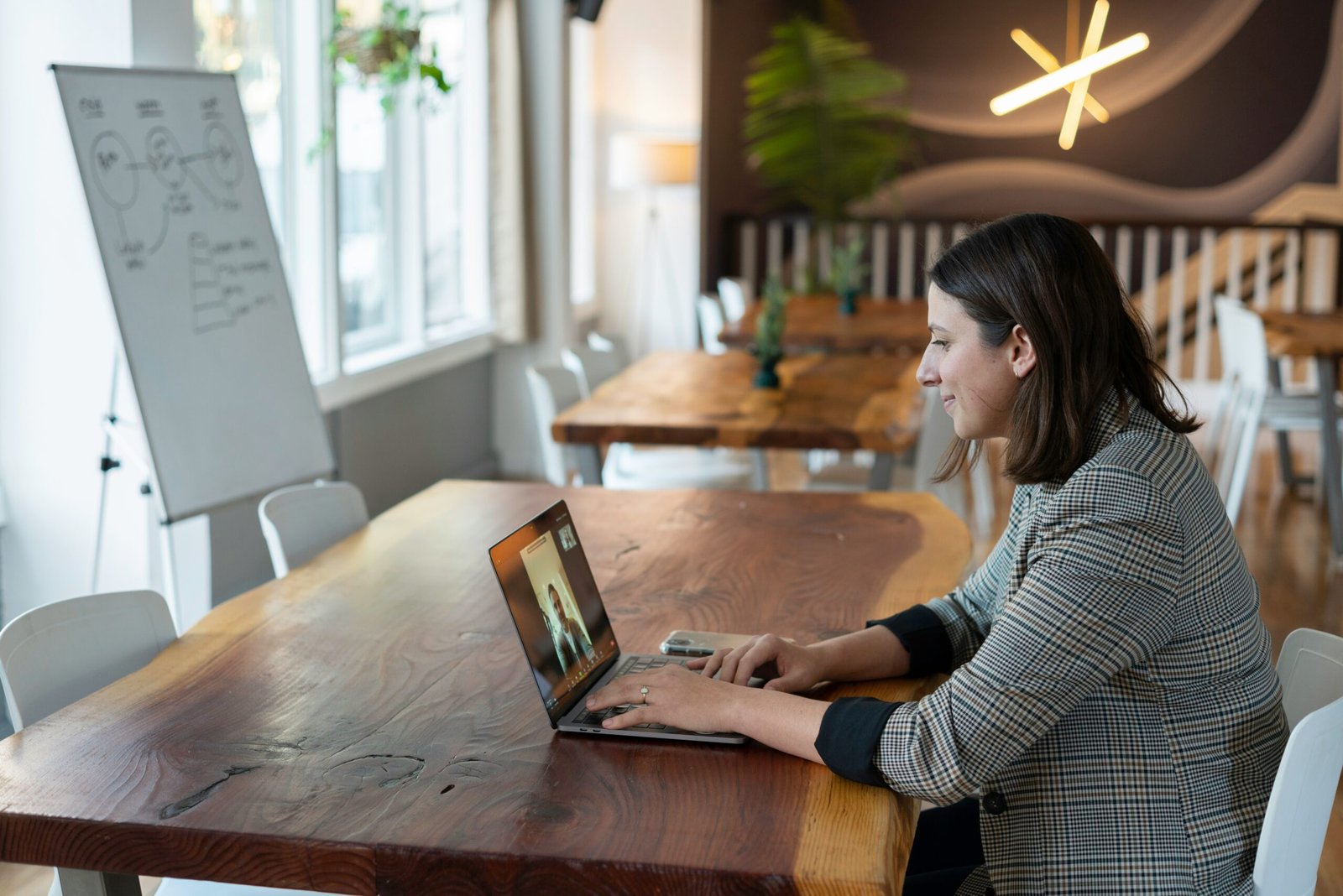 Woman on a conference call at a desk with a whiteboard to the left of the desk
