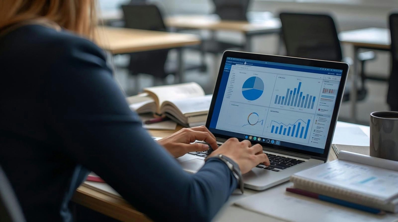 Picture of a woman's back sitting at a computer screen with various charts