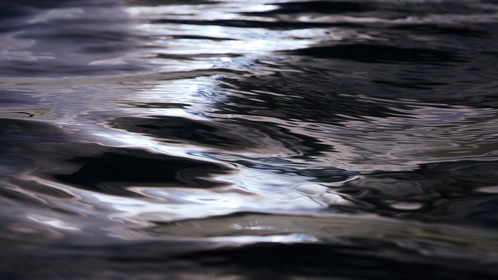 Close up of dark, flowing water with some sunshine on it